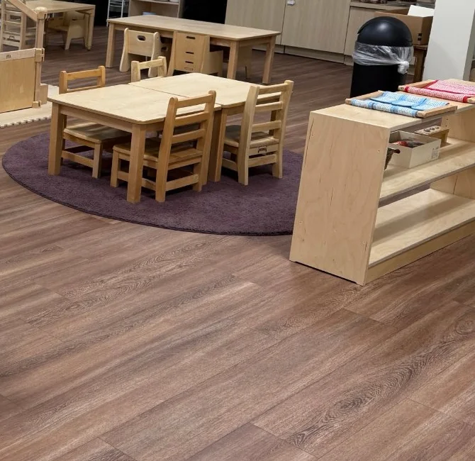 Child-sized table, chairs and low materials shelf in a school-supplied toddler room