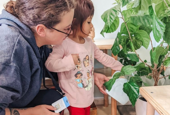 Guide supporting a child while they look at a plant together